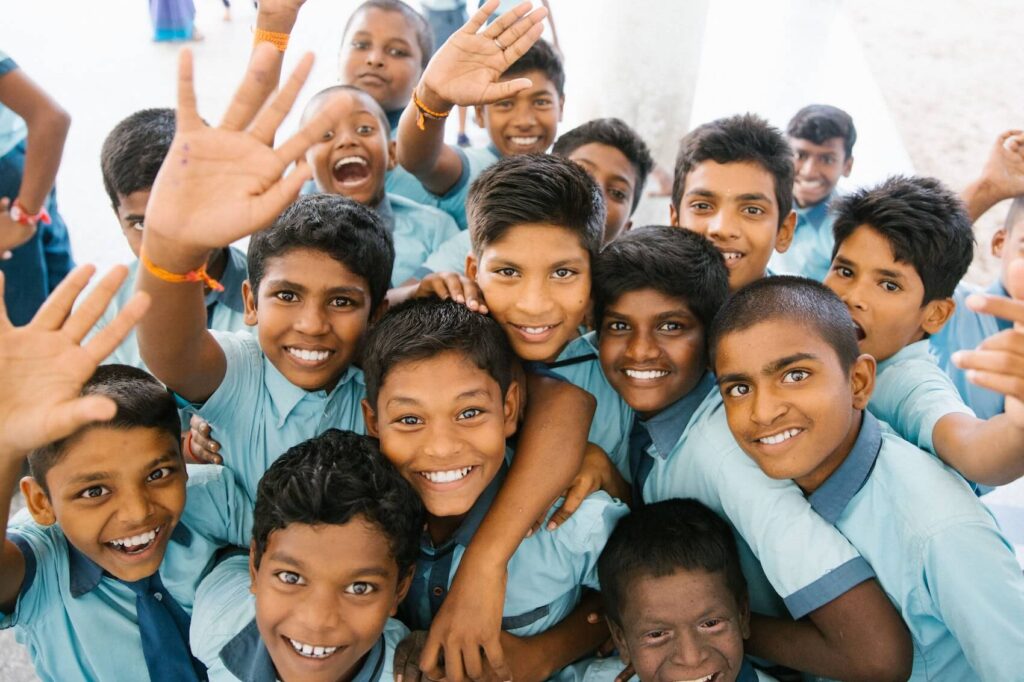 A group of school children smiling and waving at the camera